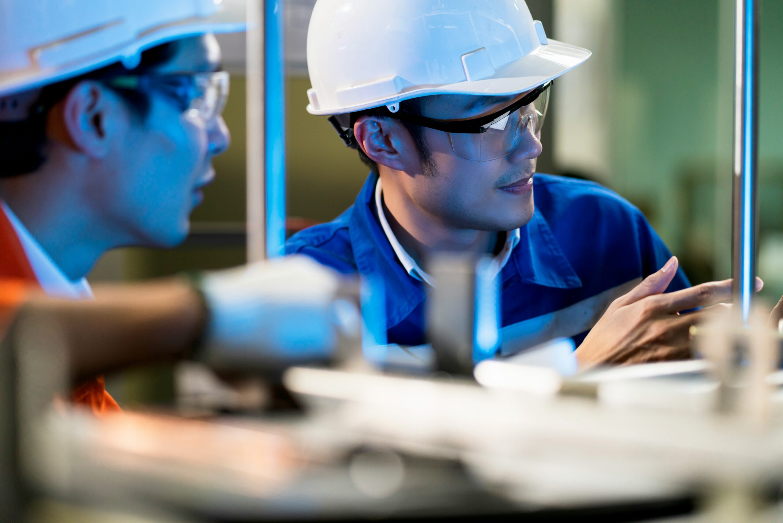 Engenheiros com capacete e óculos de segurança inspecionando instalação elétrica em campo